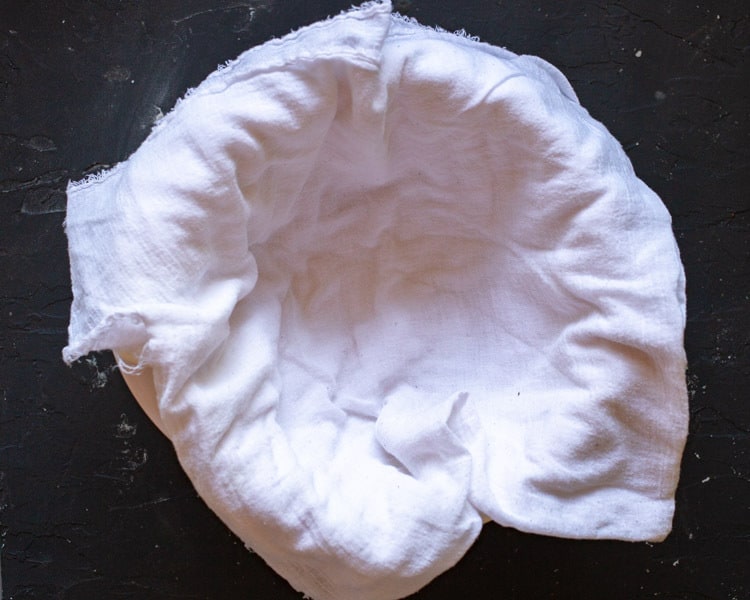 cheesecloth lining a colander in a bowl for straining